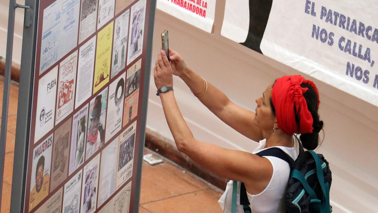 Mujer joven tomando una foto a un panel de la exposición.Exposicón en la