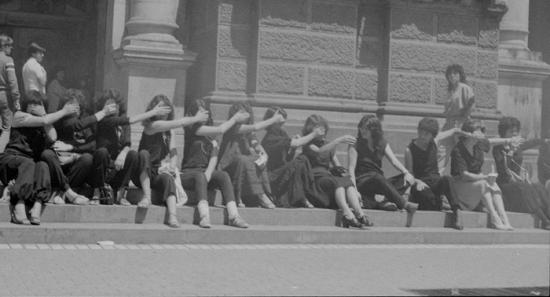 Mujeres protestando sentadas, tapándose sus bocas.